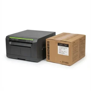 Impresora fotográfica Sinfonia CS2 reacondicionada de color gris oscuro junto a una caja de papel CHC-S6145.